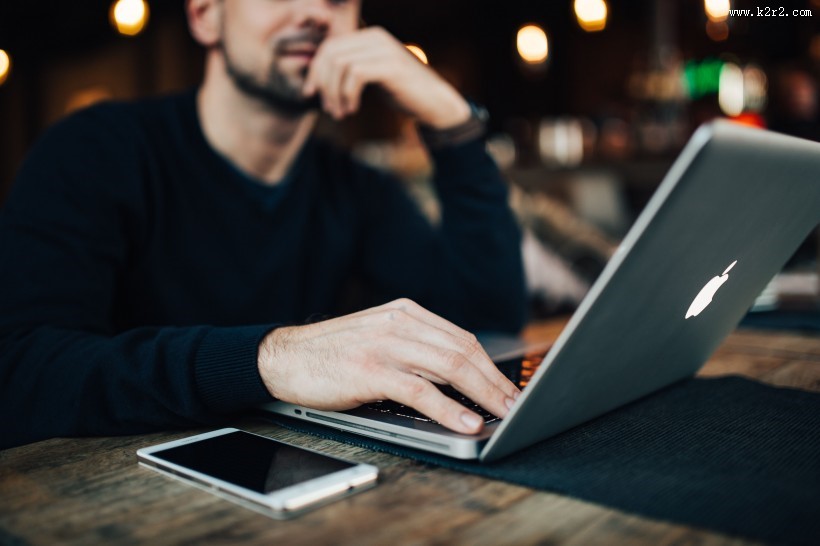 在咖啡厅使用苹果笔记本和手机的年轻男子图片