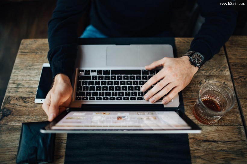 在咖啡厅使用苹果笔记本和手机的年轻男子图片