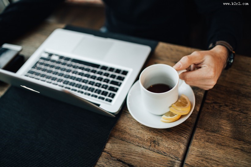 在咖啡厅使用苹果笔记本和手机的年轻男子图片