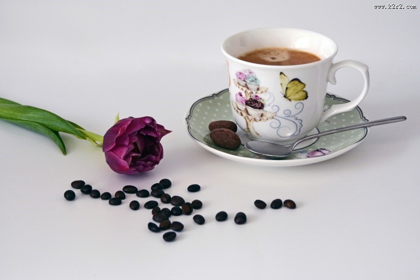 咖啡豆散落在装有咖啡的杯子旁图片大全