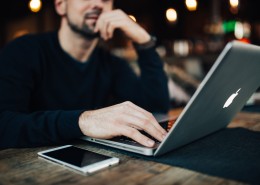 在咖啡厅使用苹果笔记本和手机的年轻男子图片